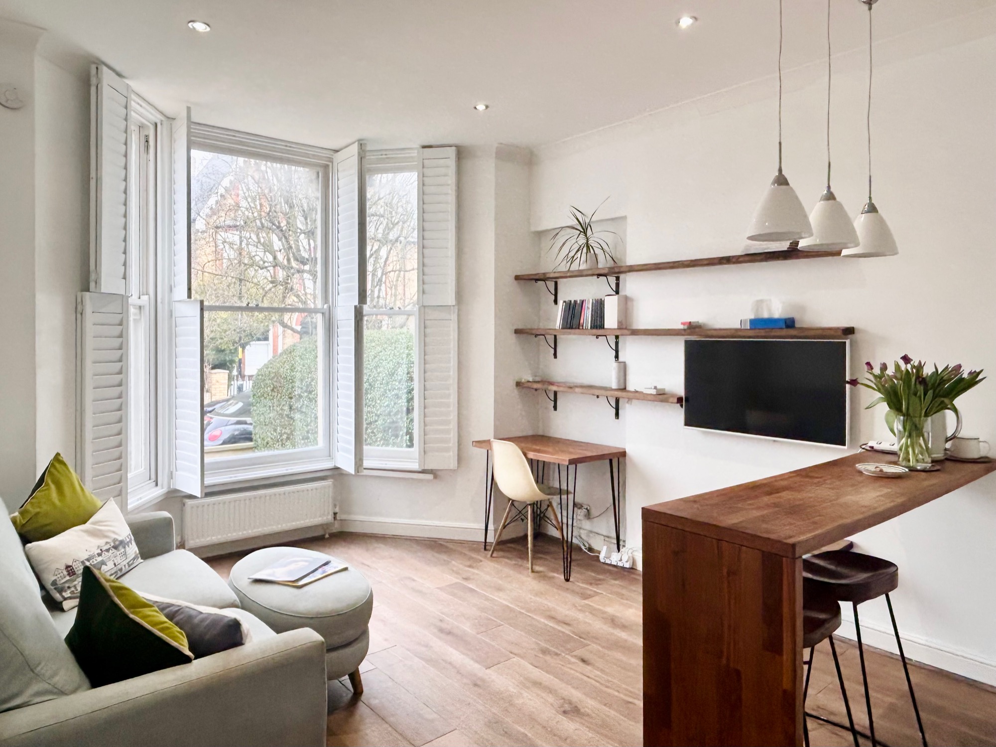 Living room with bay window, plantation shutters and built-in shelving