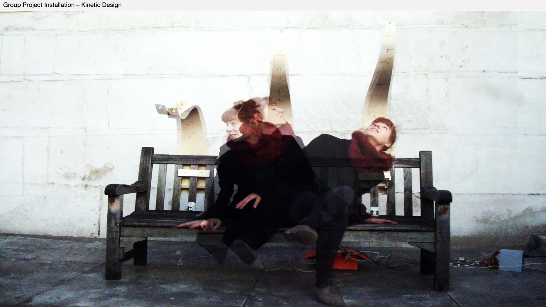 Long-exposure photograph of a kinetic design installation with moving sculptural elements on a bench