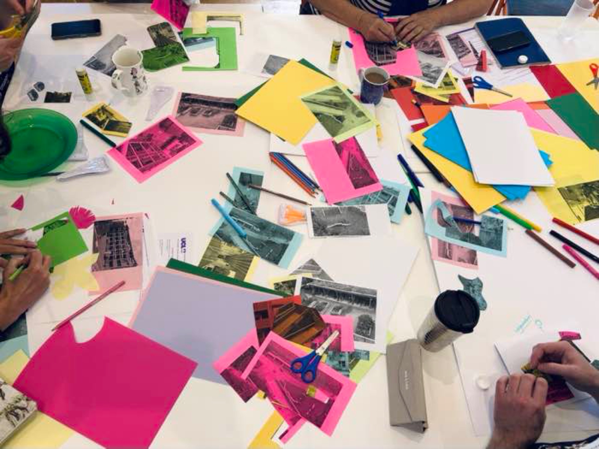 Workshop table with collage materials, cut-out photographs and coloured paper
