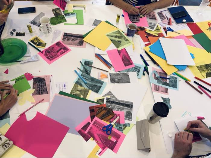 Workshop table with collage materials, cut-out photographs and coloured paper